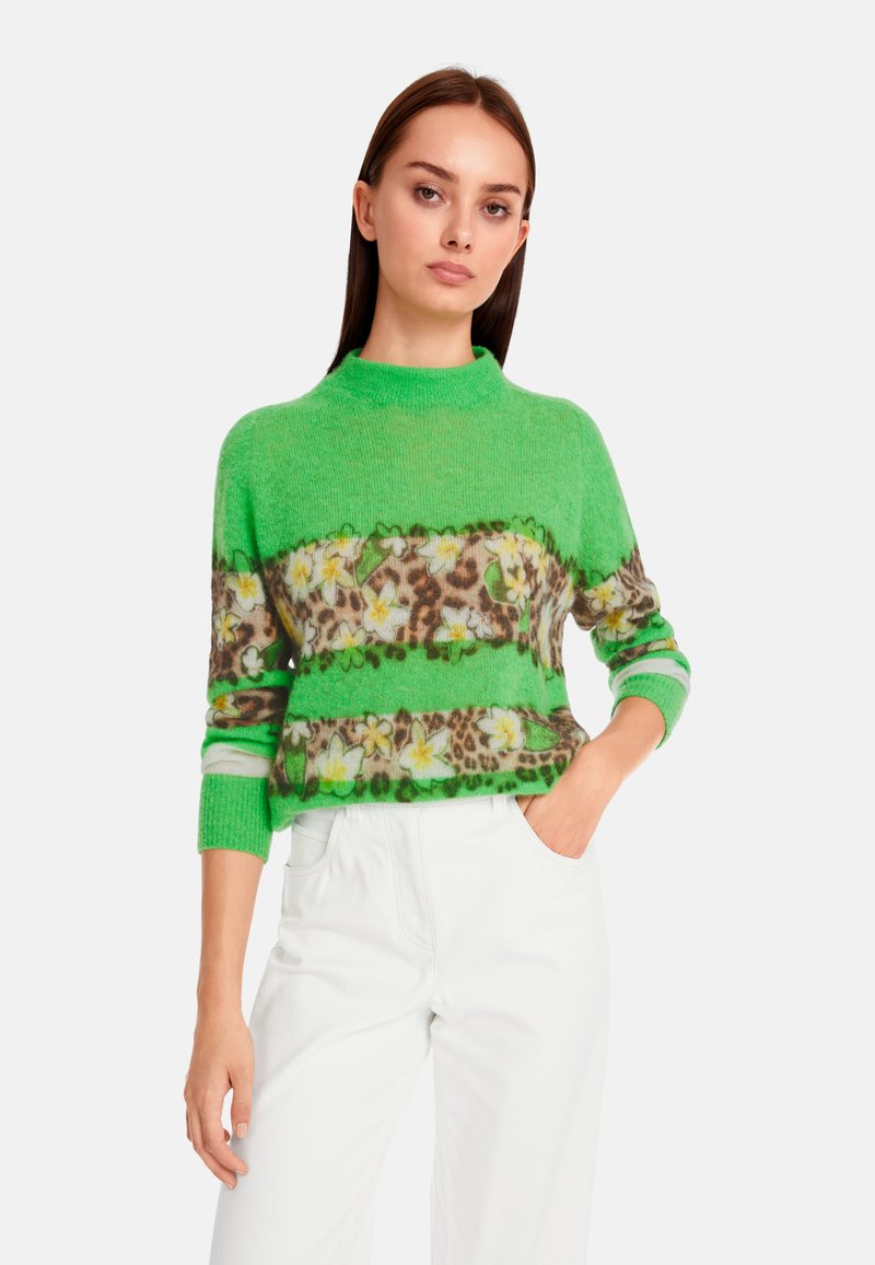 Grüner Strickpullover mit Stehkragen, verziert mit Tiermotiven und floralen Akzenten in horizontalen Streifen. Weiche Textur, Dreiviertelärmel.