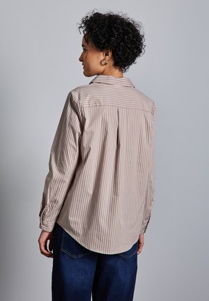 Randig blus i mjuk beige och krämfärgad, med klassisk krage, långa ärmar och rundad nederkant med en bakfålla för ökad rörelse.