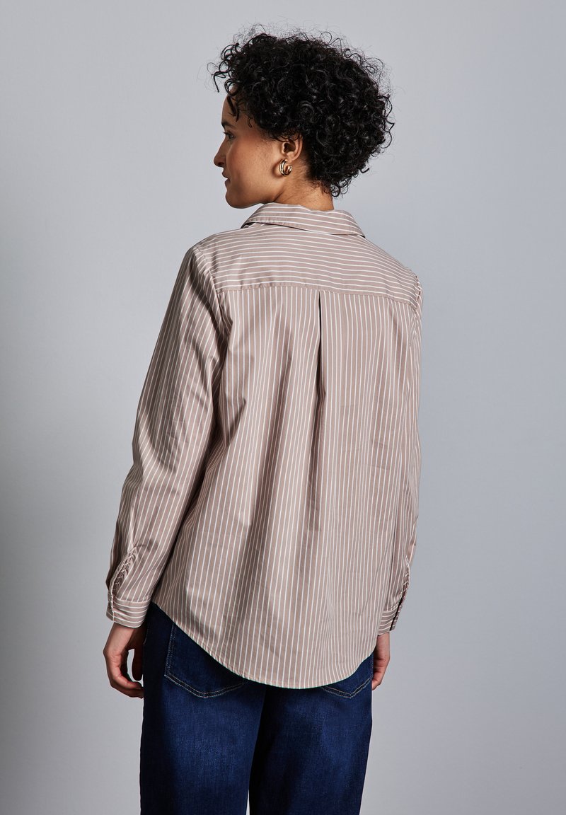 Blusa a righe in morbido beige e crema, con colletto classico, maniche lunghe e orlo arrotondato con una piega sul retro per un maggior movimento.