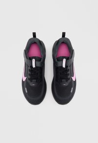 Chaussures de sport noires avec un logo swoosh rose, tige en maille texturée, col rembourré et doublure intérieure contrastée rose. Design à lacets.