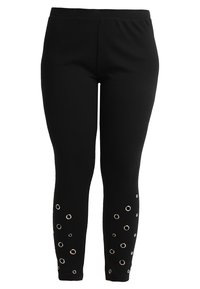 Fekete leggings rugalmas anyagból, kör alakú kivágásokkal, fém szemekkel a láb alsó részén részletezésként.