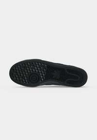 Μαύρη σόλα παπουτσιού με κυκλικά και τριγωνικά μοτίβα πέλματος, κυματιστές γραμμές στη φτέρνα και υφασμένη επιφάνεια πρόσφυσης.