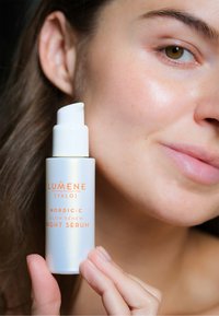 Lumene Nordic-C Glow Renew Night Serum i en matt vit flaska med pumpdispenser. Etiketten har orange text och subtil iridescens.