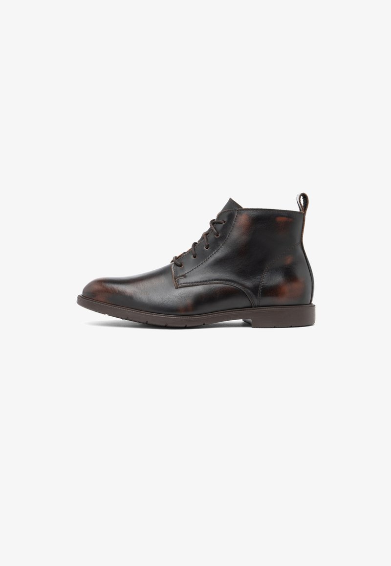 Bottine en cuir marron foncé pour homme avec lacets sur le devant, languette au talon et semelle en caoutchouc plate et basse sur fond blanc.