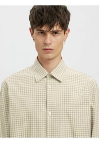 Beige rutete skjorte laget av lett stoff, med krage, knapper foran og en enkelt brystlomme.