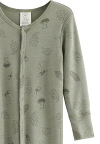 Hellgrüner Baby-Overall aus weichem Stoff mit langen Ärmeln, verziert mit zarten Drucken von Blättern, Pilzen und Igeln. Mit Druckknopfverschluss auf der Vorderseite.