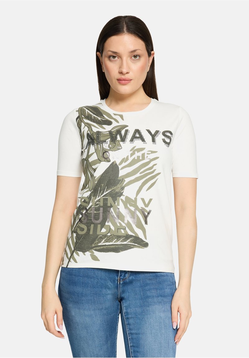 T-shirt en coton blanc avec imprimés de feuilles vertes et texte "TOUJOURS DU CÔTÉ ENSOLEILLÉ." Manches courtes et encolure ronde.