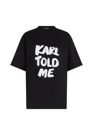 Schwarzes Baumwoll-T-Shirt mit kurzen Ärmeln und lockerer Passform. Auf der Vorderseite steht der Text "KARL TOLD ME" in fetter, weißer Pinselstrich-Schrift.