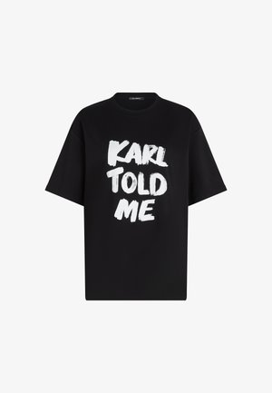 T-shirt en coton noir avec des manches courtes et une coupe décontractée. Le devant arbore le texte "KARL M'A DIT" en lettres blanches en coup de pinceau.