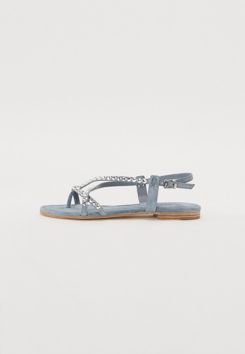 Light blue suede sandal with flat sole, featuring decorative silver studs along the straps and an ankle buckle for adjustability.