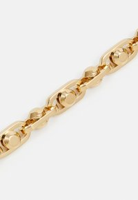 Goldenes Gliederarmband mit rechteckigen und abgerundeten Gliedern, die erhabene runde Nieten auf weißem Hintergrund haben.