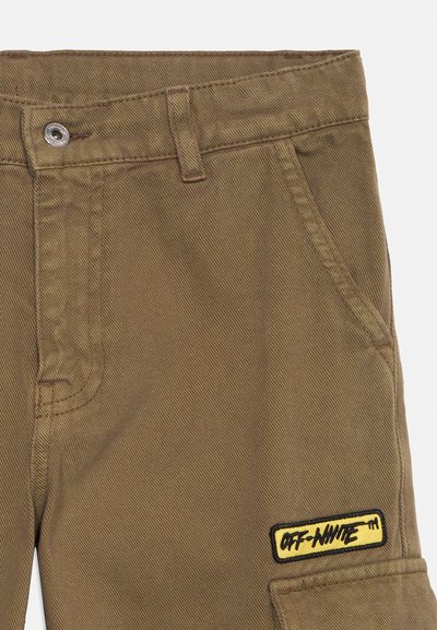 Καφέ παντελόνια με εμπρόσθια τσέπη, κλείσιμο με μεταλλικό κουμπί, θηλιές για ζώνη και κίτρινο έμπλαστρο "OFF-WHITE" κοντά στην κάτω δεξιά τσέπη.