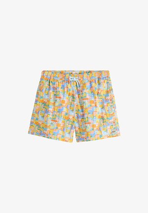Mand iført farverige badeshorts med et bylandskabsmønster og en orange snor bundet ved taljen.
