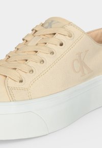 Μπεζ καμβάς sneaker με μπεζ κορδόνια, ανυψωμένη λευκή λαστιχένια σόλα και λεπτό λογότυπο "cK" στο πλάι και στη γλώσσα.
