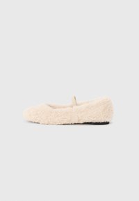 Fluffy, cream-colored slipper with a soft texture, rounded toe, minimal design, and a small fabric loop on the back for easy wear.