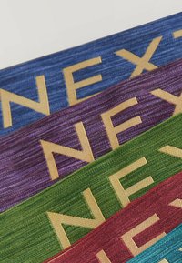 Rubans tissés empilés en bleu, violet, vert et rouge, chacun avec des lettres majuscules dorées formant « NEX ».