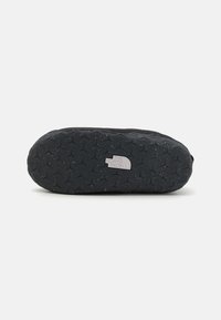 Scarpa da ginnastica nera con suola in gomma texturizzata caratterizzata da un motivo triangolare e un piccolo badge con logo sul lato.