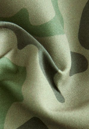 Camouflage fabric in shades of green and beige. Textured with smooth, draping quality and irregular pattern of dark green and light beige shapes.