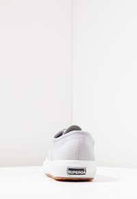 Baskets en toile grise à profil bas, semelle en caoutchouc blanche et arrière texturé. Présentent un logo Superga noir sur le talon.