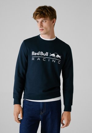 Marineblauwe sweatshirt met lange mouwen met het "Red Bull Racing" logo in het wit. Fitted ontwerp, geribde manchetten en tailleband. Gladde textuur.