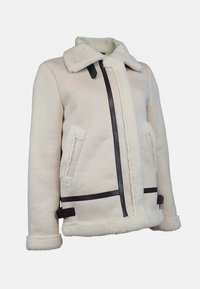 Veste en shearling crème avec un col à revers. Comprend des accents en cuir noir, deux poches latérales et une fermeture éclair frontale.