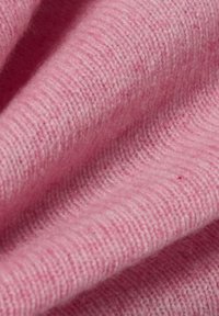 Weiches, rosa Strickgewebe mit enger, gleichmäßiger Textur und subtilen Faserabweichungen. Keine sichtbaren Muster oder Akzente. Fokus auf sanften, fließenden Falten.
