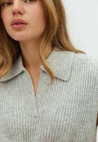 Maglione grigio in lana a coste con colletto ripiegato e scollo a V profondo. Presenta una consistenza morbida e un design a vestibilità rilassata.