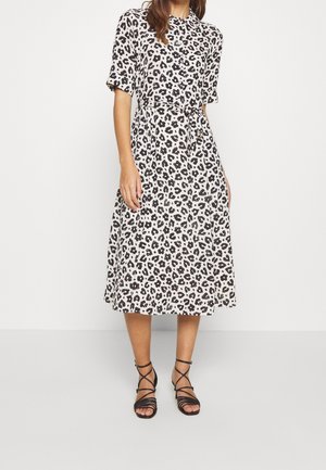 Beige leopard print midi kjole med korte ærmer, bælte i taljen og en svævende silhuet. Et par sorte strop sandaler fuldender looket.