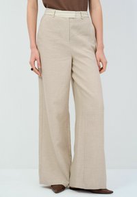Beige wijduitlopende trousers gemaakt van gestructureerde stof, met een contrasterende riem en een hoge taille, met strakke lijnen en zonder zichtbare versieringen.