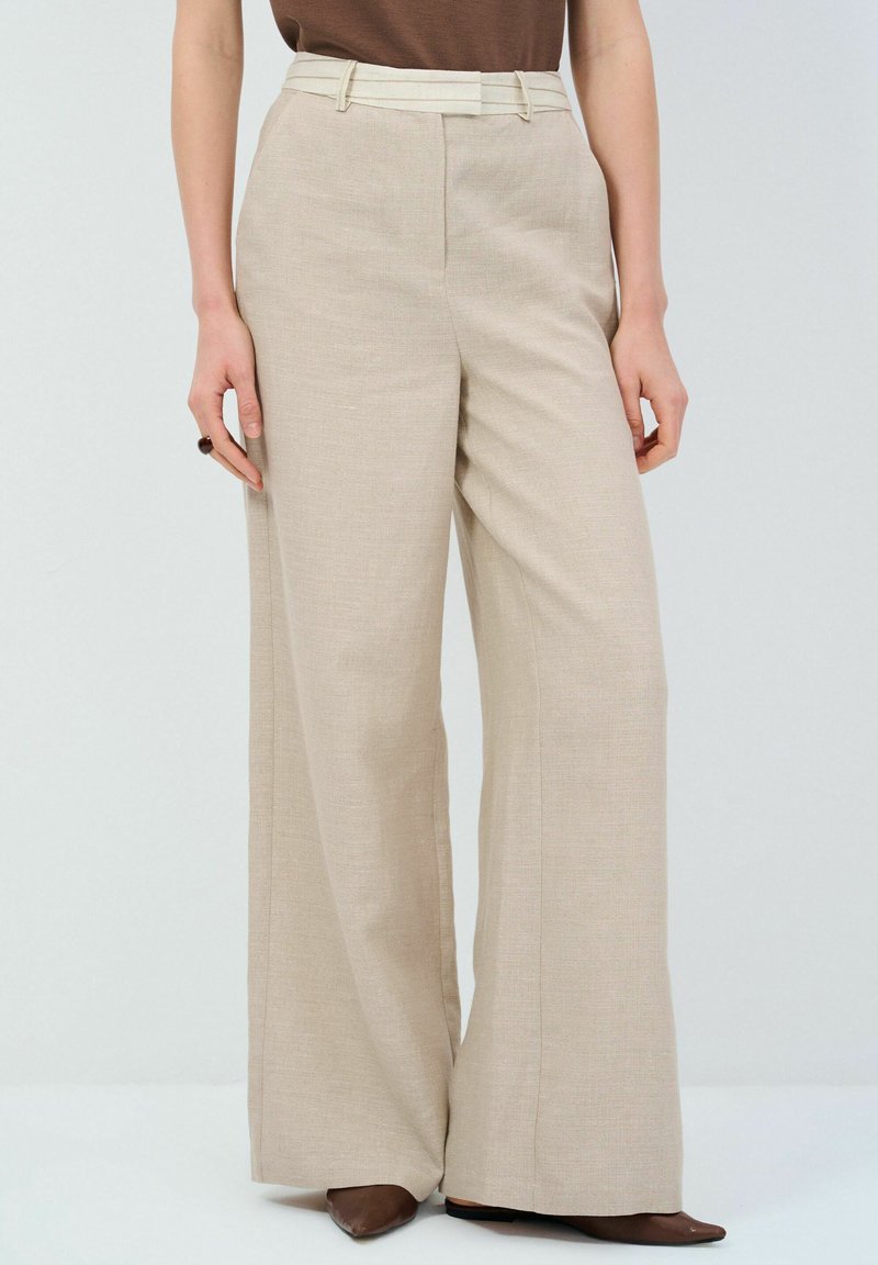 Beige wijduitlopende trousers gemaakt van gestructureerde stof, met een contrasterende riem en een hoge taille, met strakke lijnen en zonder zichtbare versieringen.