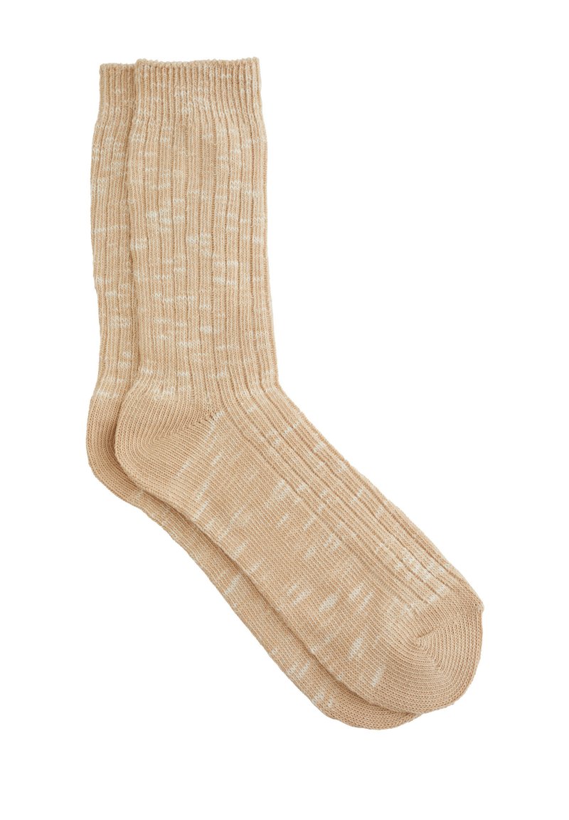 Beige strikkede sokker med ribbet tekstur, der har et pletmønstret design og en sømløs tå. Blødt materiale for komfort.