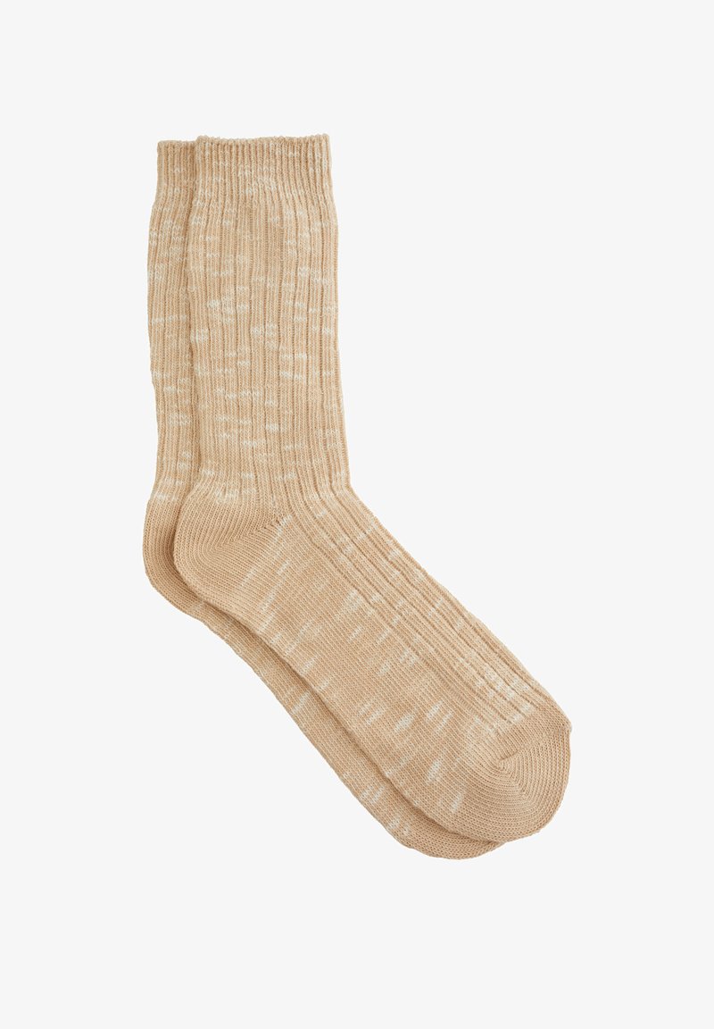 Beige kötött zoknik bordázott textúrával, foltos mintával és varrás nélküli lábujj kialakítással. Puha anyag a kényelemért.
