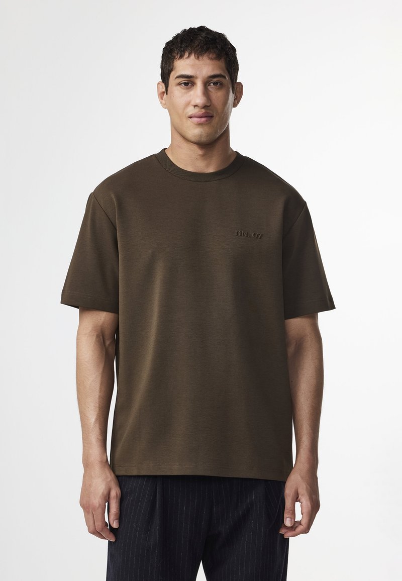 Olivengrøn bomuld t-shirt med korte ærmer, en rund halsudskæring og et diskret præget "NN. 07" logo på brystet. Glat tekstur.