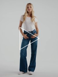 Bijela uska majica uparena s plavim trapericama visokog struka i širokih nogavica. Ima zatvarač na kopčanje i nježni poderani rub.