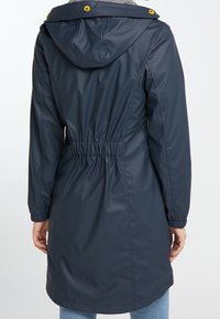 Navy waterproof parka with a drawstring waist, elastic cuffs, and a hood. Features yellow hardware and a grey lined interior.