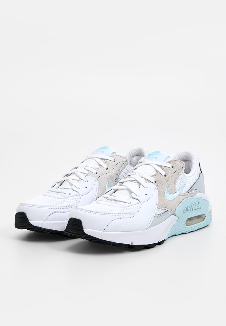 Zapatillas blancas y gris claro con un diseño texturizado, acentos azules y una unidad de amortiguación visible en el talón. Suela de goma negra.