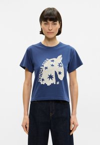 Μπλέ εμπριμέ μπλουζάκι από βαμβάκι, με λευκή γραφική απεικόνιση κεφαλής αλόγου και αστέρια. Έχει κοντά μανίκια, στρογγυλή λαιμόκοψη και χαλαρή εφαρμογή.