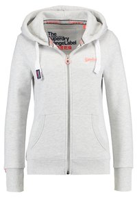 Felpa grigia chiara con zip, dotata di un ampio cappuccio, tasche frontali e polsini a coste. Presenta un logo ricamato sul petto e lacci a contrasto.