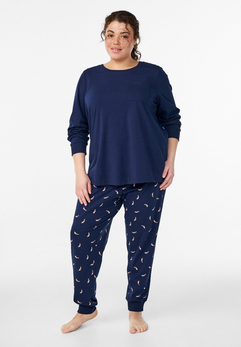 Tumši zils garroku tops ar kabatu un pidžamas bikses ar ziedu rakstu. Mīksts audums ar brīvu piegriezumu un elastīgām aprocēm pie potītēm.