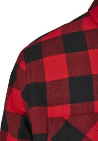 Rød og svart rutete flanellskjorte, med et sjakkmønster, myk tekstur og en strukturert krage, som fremhever et klassisk design.