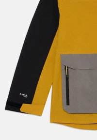 Gelb- und schwarze Jacke mit einer grauen Tasche mit Reißverschluss, strukturiertem Stoff und dem "A.W.S. ACTIVE"-Branding am Ärmel.