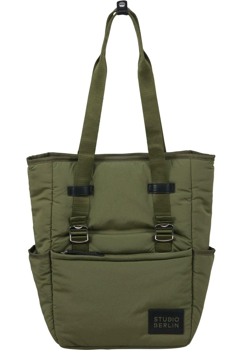 Tote bag olivinvihreästä pehmustetusta kankaasta, jossa on kaksi yläkahvaa, säädettävät hihnat ja edessä vetoketjullinen tasku, jossa on brändilogo.