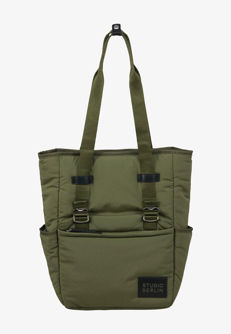 Borsa tote verde oliva in tessuto imbottito, dotata di due manici superiori, spallacci regolabili e una tasca frontale con zip e etichetta di branding.