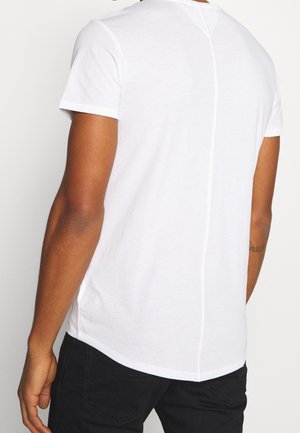 Witte korte mouw t-shirt met een afgeronde zoom, voorzien van een naadtoevoeging die verticaal over de rug loopt. Gemaakt van katoen met een gladde textuur.