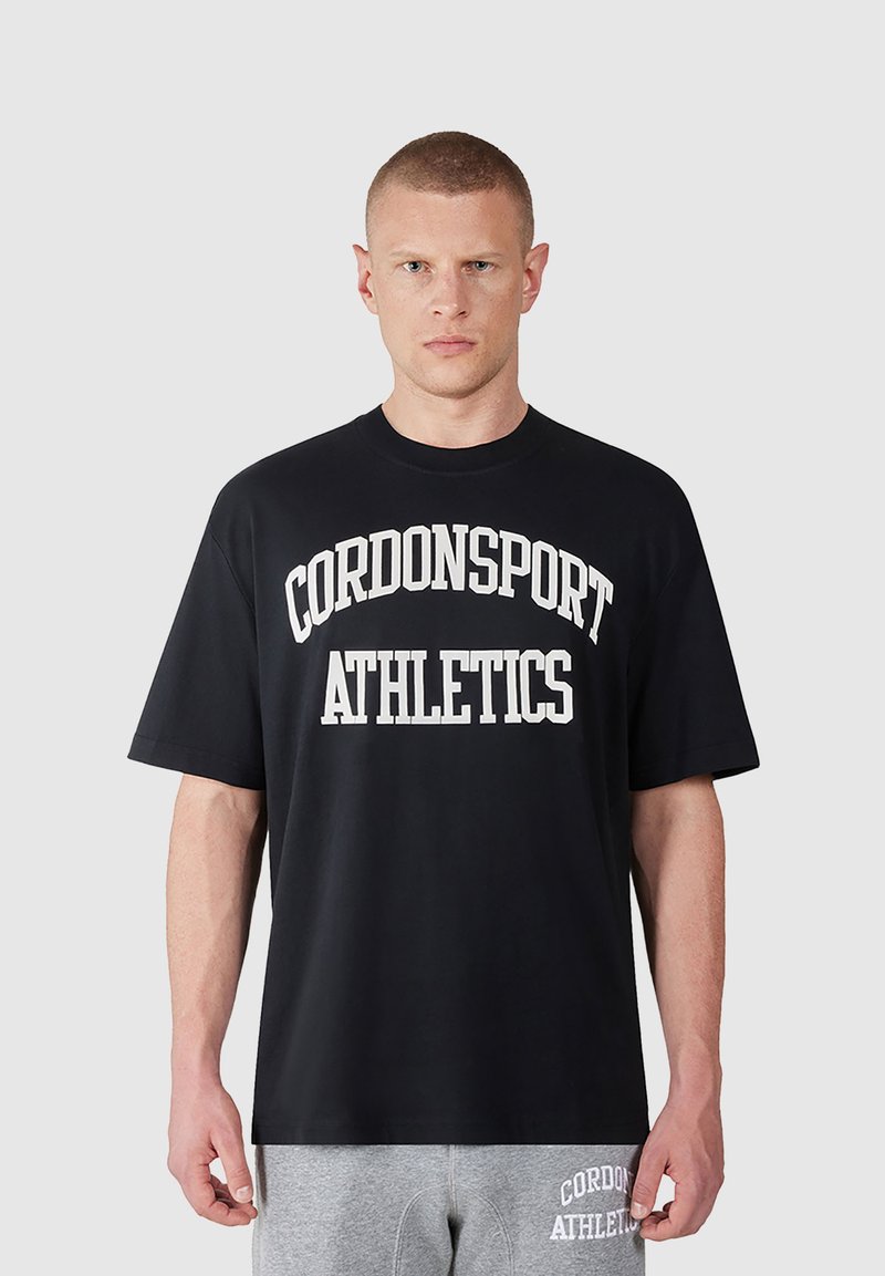Schwarzes Baumwoll-T-Shirt mit fett gedrucktem weißen Text "CORDONSPORT ATHLETICS" in einem gewölbten Design. Kurze Ärmel und lockere Passform.
