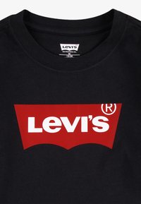 Crna pamučna majica s okruglim izrezom, s istaknutim crvenim logom na kojem bijelim slovima piše "Levi's" unutar zakrivljene crvene vrpce.