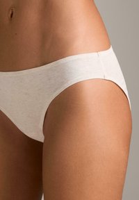 Biele bavlnené slipy s hladkou textúrou, s nízko posadeným pásom a minimálnymi švovými detailmi, zobrazené na neutrálnom pozadí.