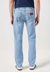 Jeans in denim di un azzurro chiaro con taglio dritto, due tasche posteriori con cuciture decorative e una targhetta in pelle in vita.
