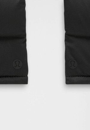 Czarne, pikowane sekcje materiału z wytłoczonym logo Lululemon w pobliżu dolnych krawędzi na jasnoszarym tle.