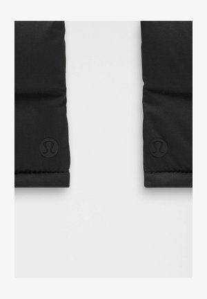 Czarne, pikowane sekcje materiału z wytłoczonym logo Lululemon w pobliżu dolnych krawędzi na jasnoszarym tle.